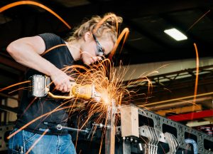 female trade worker grinds and cuts metal